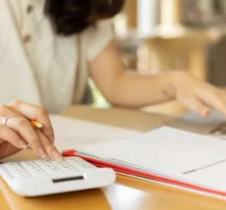 person calculating wages using a calculator and spreadsheet 