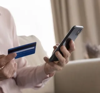 elderly person holding phone and card in hands