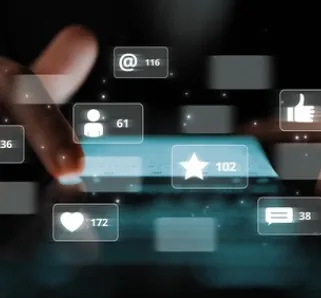 pair of hands scrolling through a phone with various social media icons popping up showing a variety of likes, comments, and other means of communicating via social media and videos. 