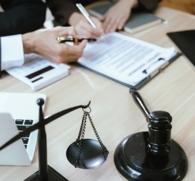 lawyers working on papers with scale and gavel nearby 