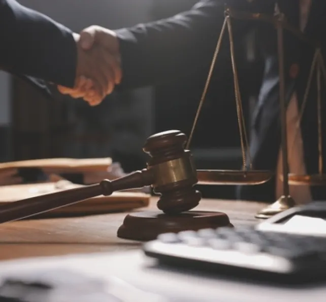 two people shaking hands with scales and gavel nearby
