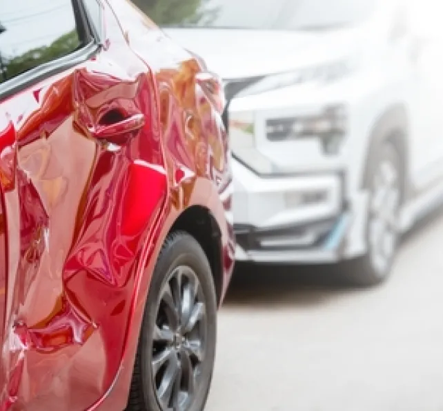 red and silver car in a accident, the red car has a dent in the back 