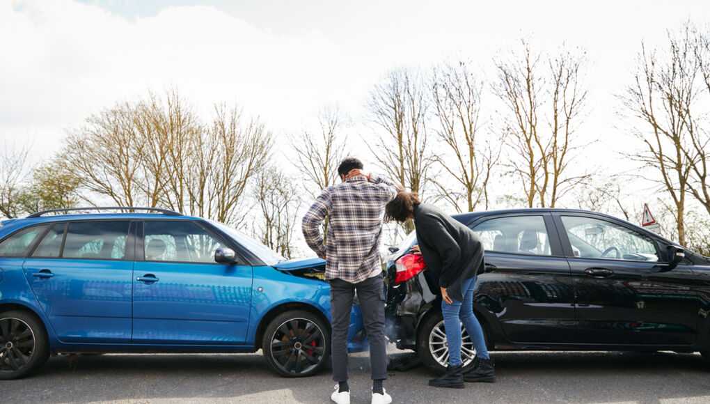 Two people inspecting damage on cars after a minor collision in a parking lot