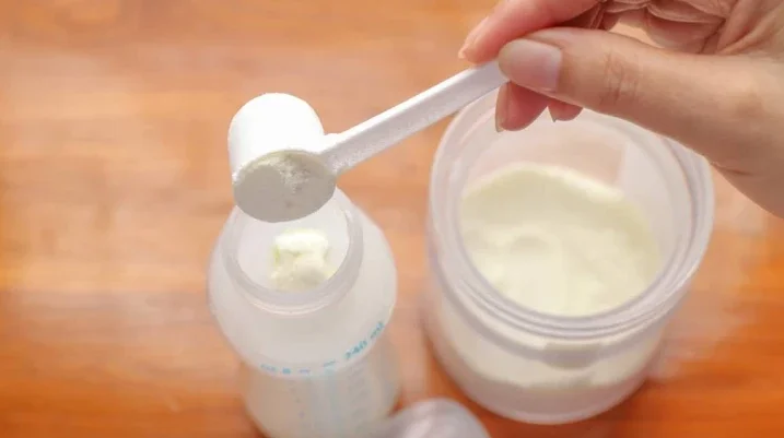 putting baby formula into a baby bottle
