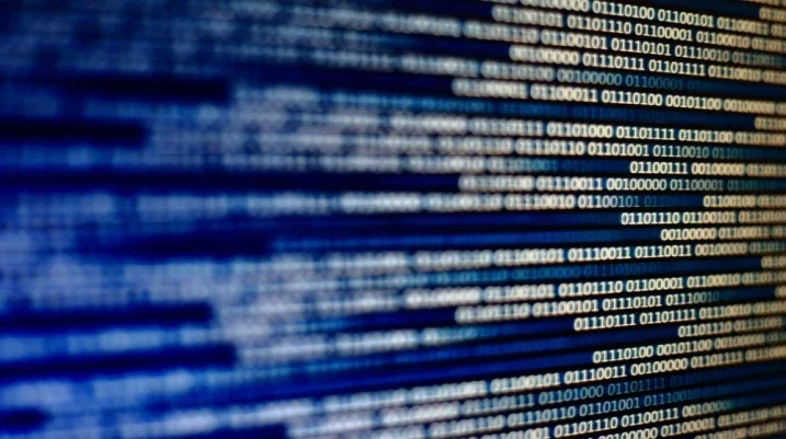 Close-up of computer screen displaying binary code in blue and white, highlighting data and cybersecurity.