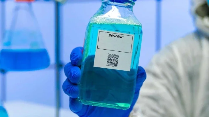 Someone in a lab holding a bottle of benzene