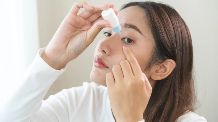 Woman putting in eye drops