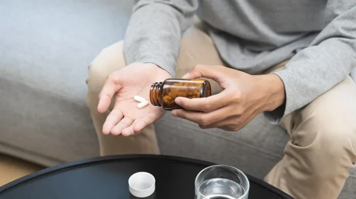 Man sitting on a couch with pills in hand