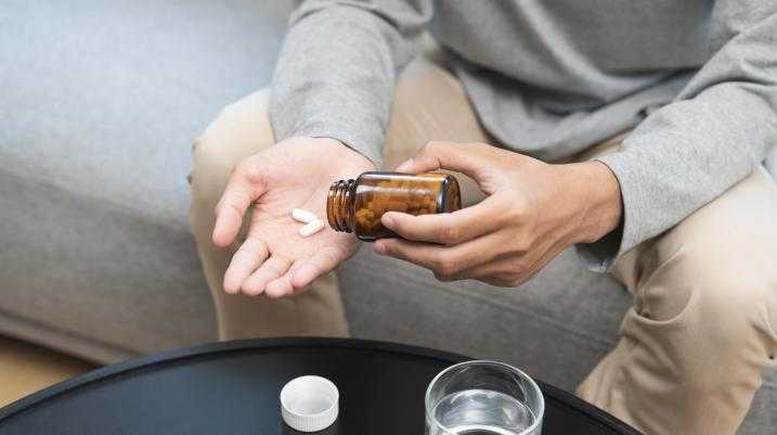 Man sitting on a couch with pills in hand