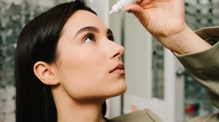 Woman putting in eye drops