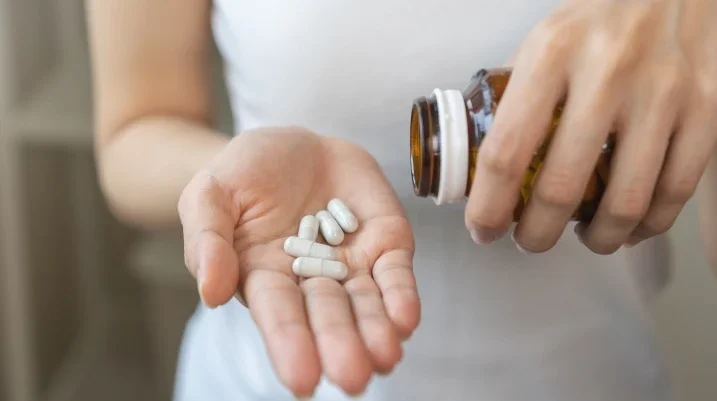 Woman pouring supplements into hand