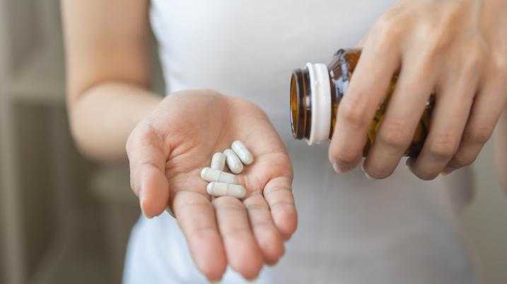 Woman pouring supplements into hand