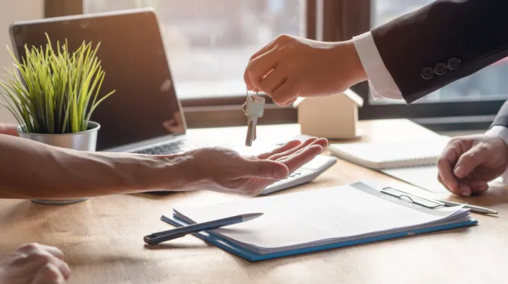 Realtor agent giving a key of apartment to new owner after signed lease agreement.