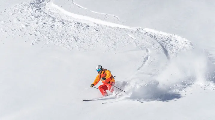 one freeride skier skiing downhill trough deep fresh powder