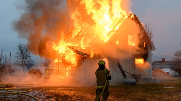 Firefighter using a hose on a house fire