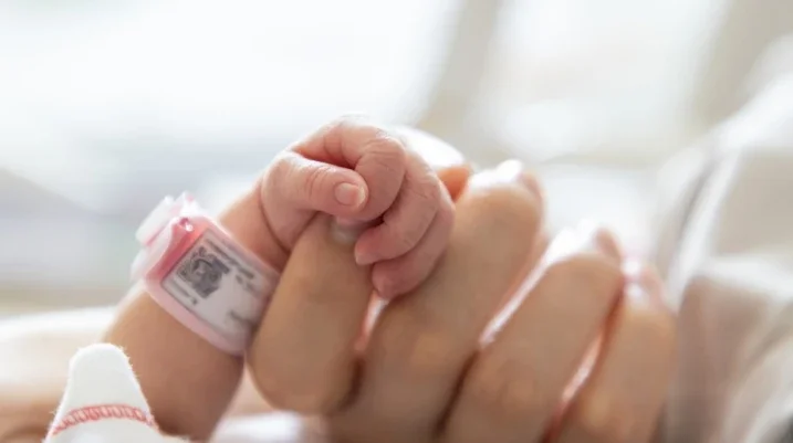 newborn baby holding onto moms hand