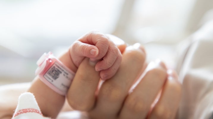 newborn baby holding onto moms hand