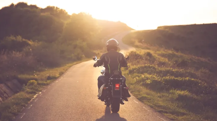 Motorcycle rider on the road in sunset light. Travel and sport, speed and freedom concept.