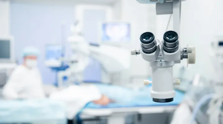 Lasik treatment operation, laser vision correction. Doctor examines fundus in microscope, patient under sterile cover.