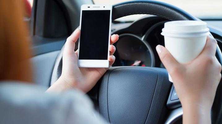 What is Tennessee Doing to Combat the Rise of Distracted Driving? - A man in a car with a cup of coffee and mobile phone