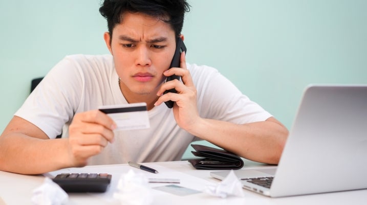 Man on phone looking at card