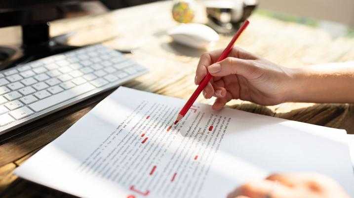 Close-up Of A Person's Hand Marking Error With Red Marker On Document