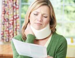Woman in neck cast looking at paper and holding neck