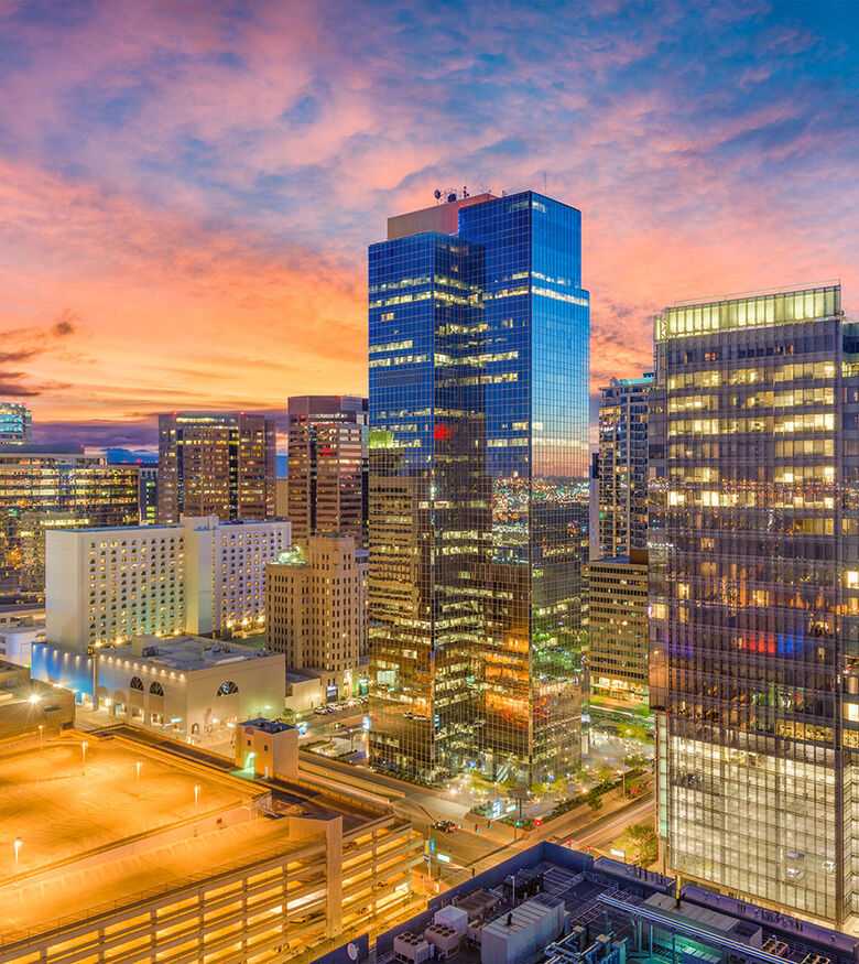 Phoenix cityscape at dusk with illuminated skyscrapers under a vibrant sunset sky, ideal for personal injury lawyers.