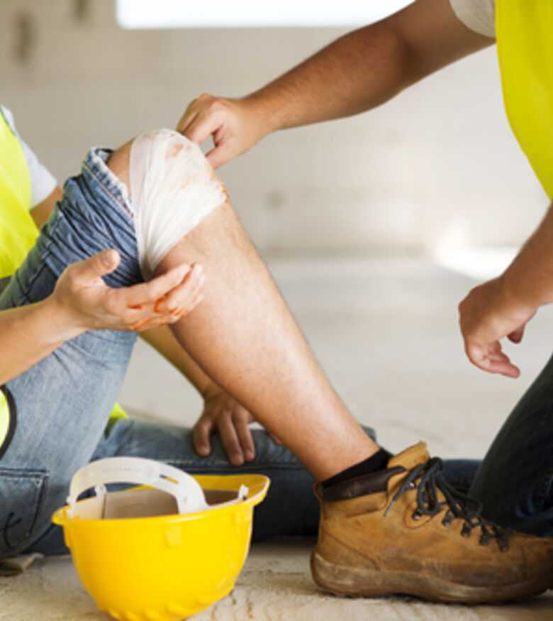 Construction worker receiving first aid for a leg injury, contact a lawyer in Panama City.