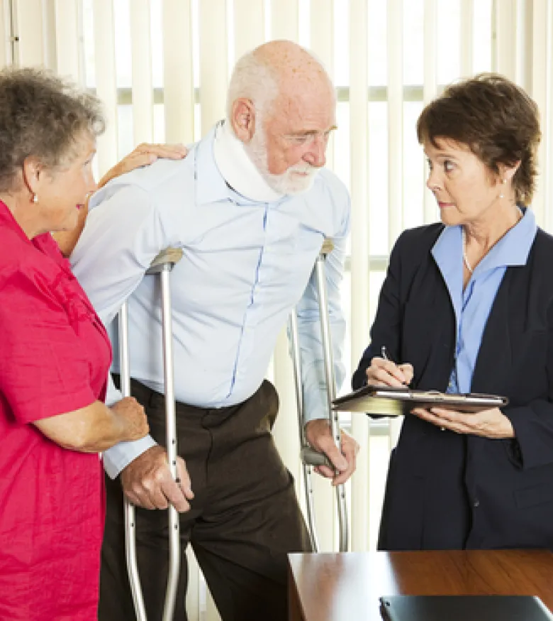 An elderly man on crutches speaking with a lawyer, emphasizing the need for an Injury Attorney in Queens to provide legal assistance.