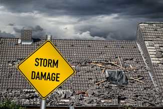 Hurricane Insurance Claim Attorneys in New York - Wrecked Roof with storm damage sign