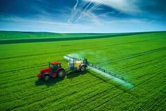 Aerial view of farming tractor plowing and spraying on field.