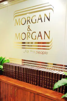 Office interior with "Morgan & Morgan" logo on a glass wall, framed by elegant gold lines.