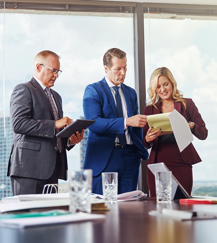 Attorneys standing by a conference table looking at documents and contemplating their meaning