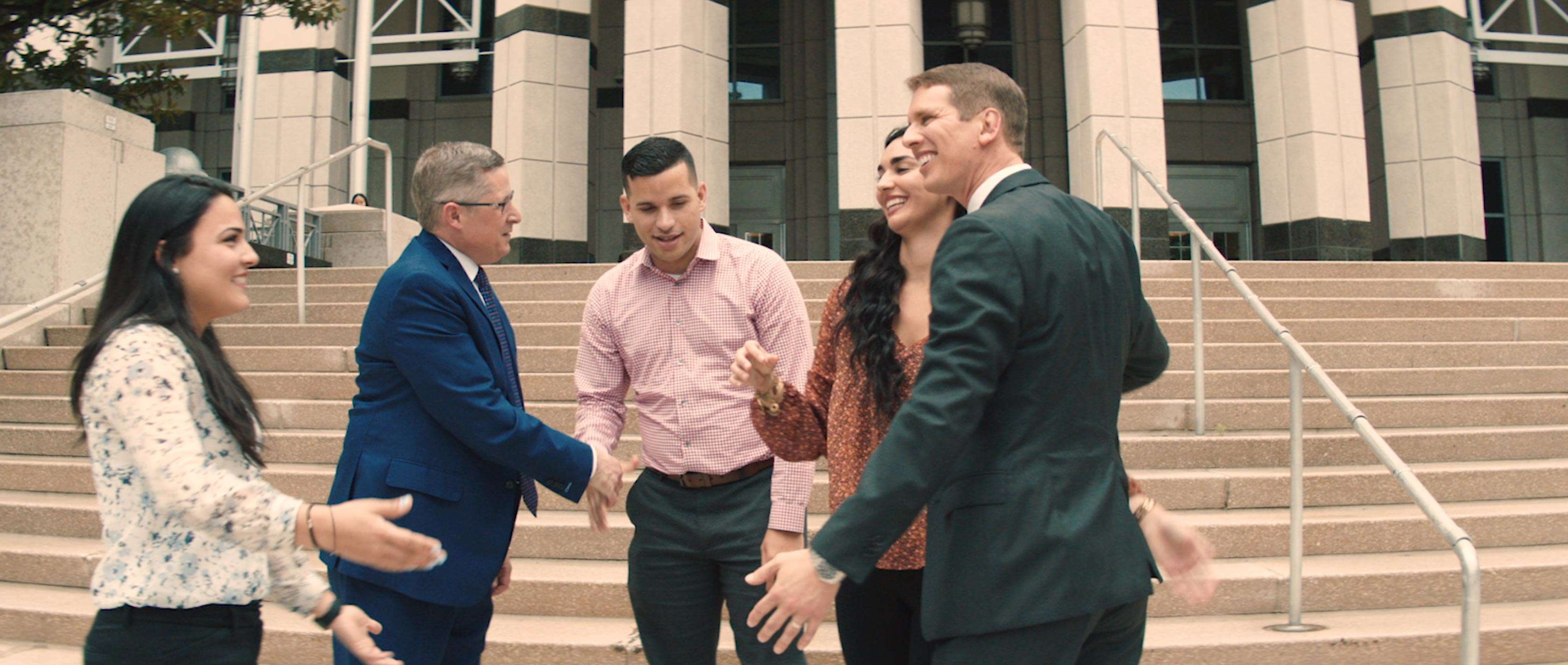 Lawyers shaking hands with their clients in front of a courthouse